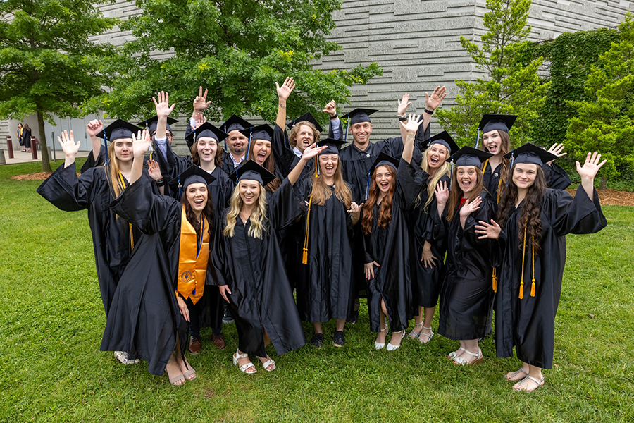 Graduates in caps and gowns outside after commencement