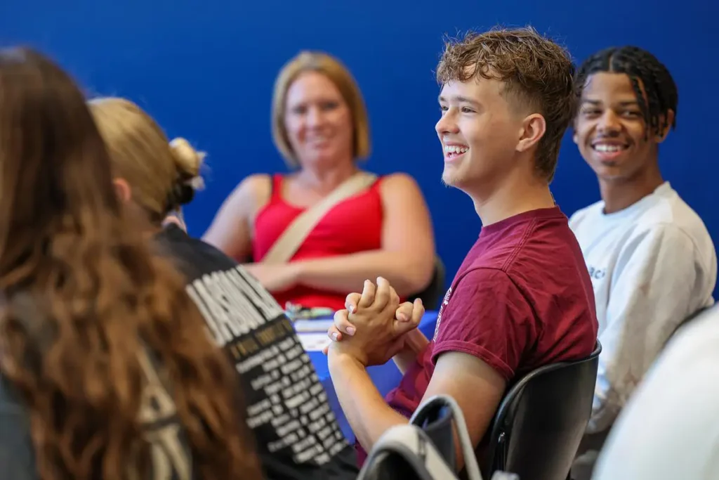 Students smiling and laughing while sitting together during a bingo event.