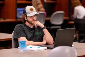 Student studies in the OTC library with a laptop and notebook.