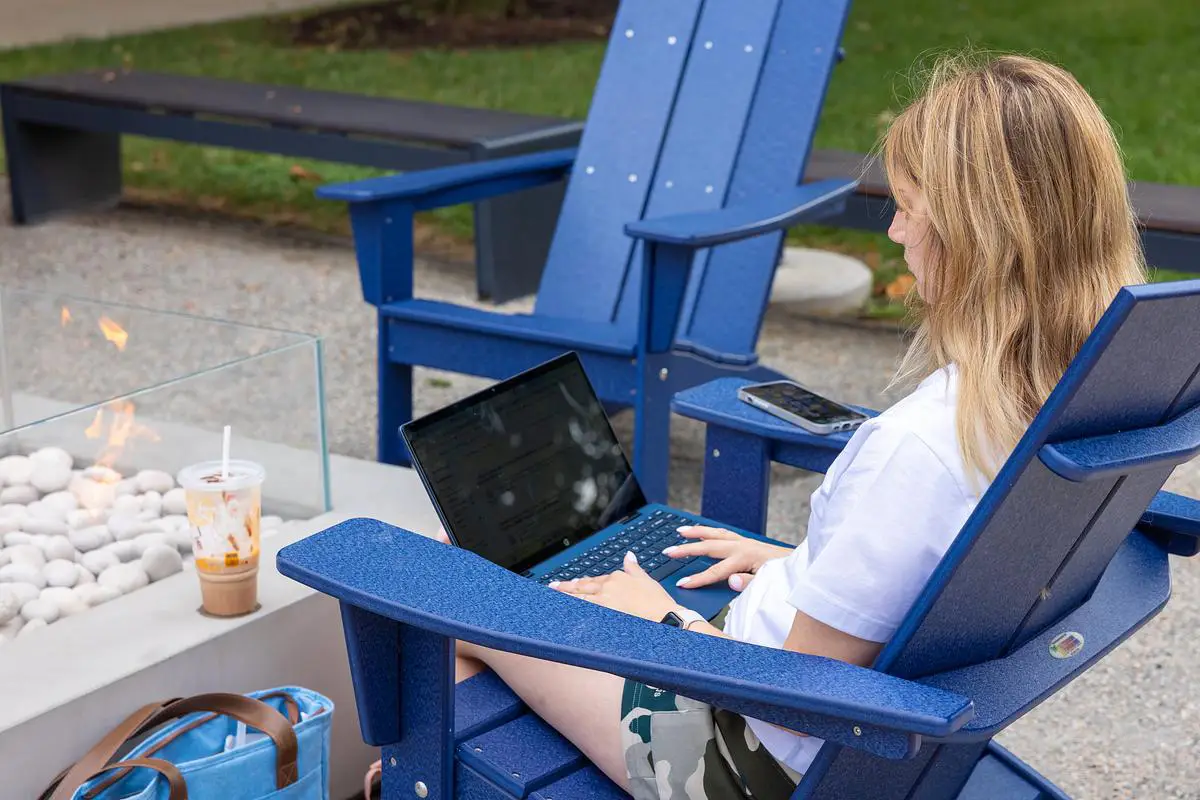 Student studies on a laptop while seated by the outdoor firepit at Ozarks Tech.