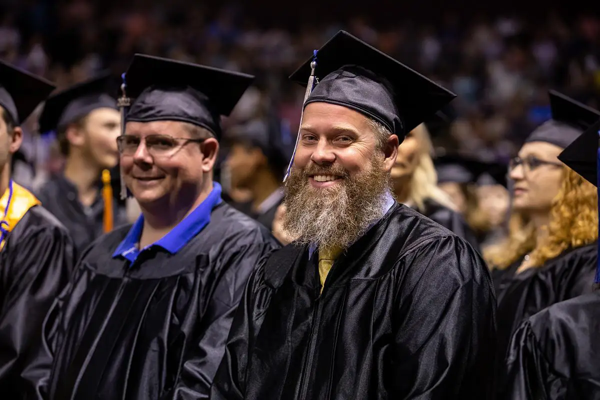 Smiling graduates in caps and gowns seated during OTC commencement ceremony.
