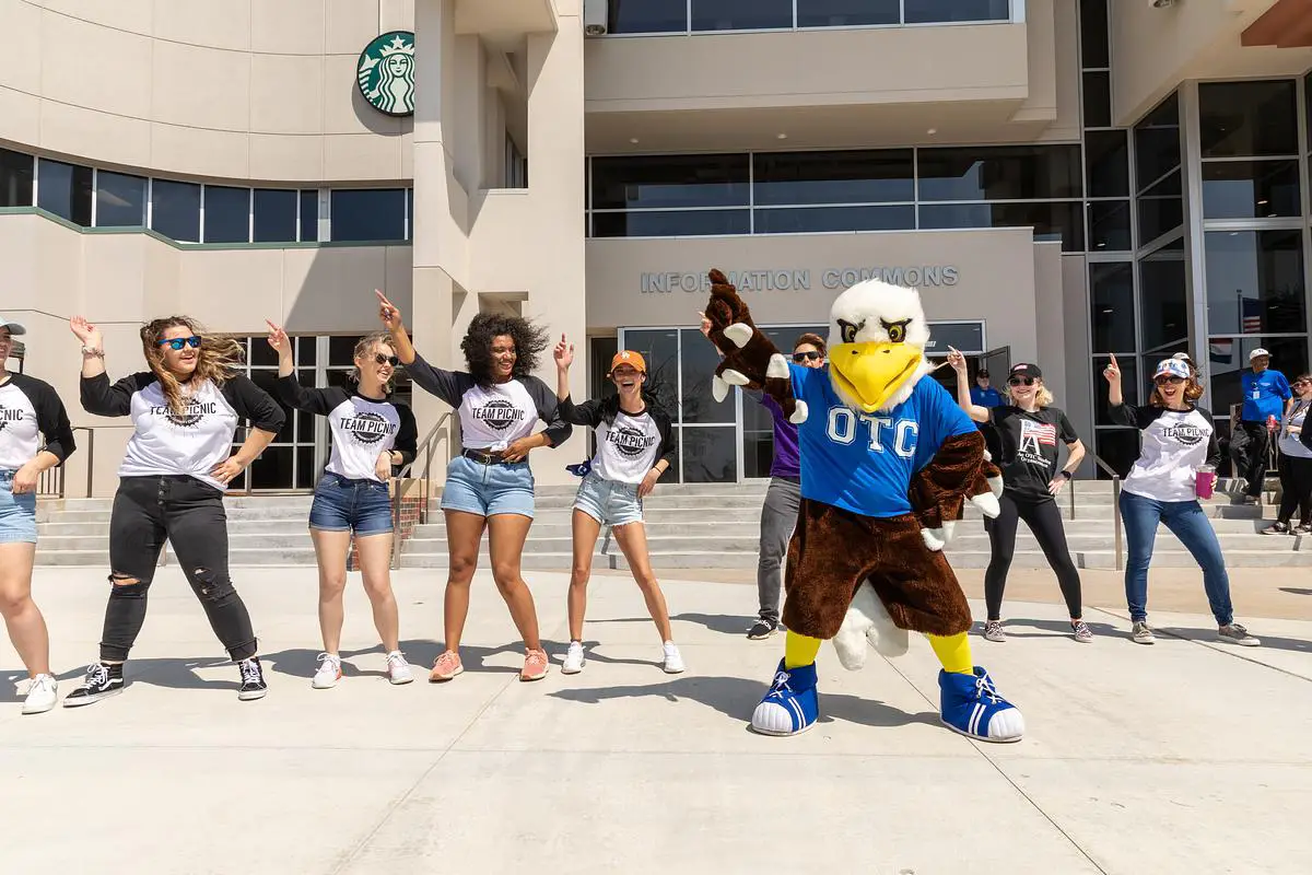 Ozzy the Eagle dances with students outside the OTC Information Commons during a campus picnic.