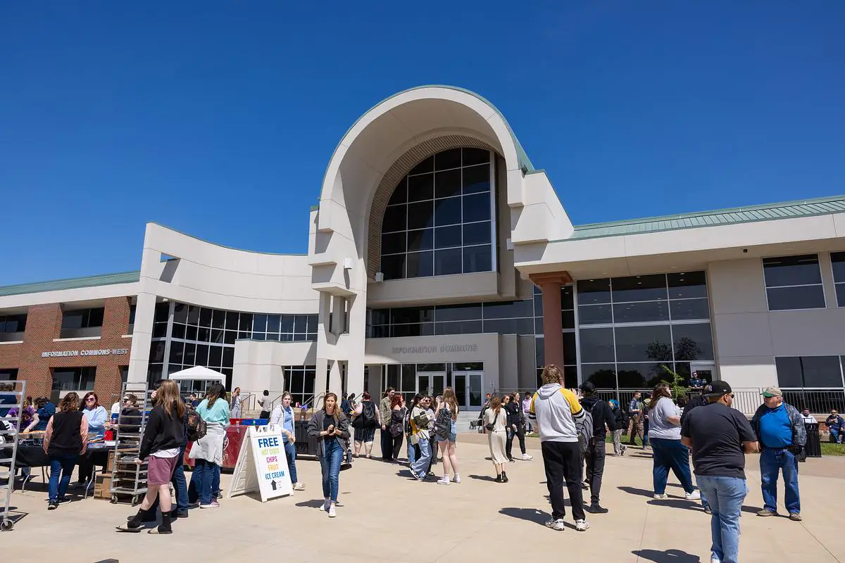 Students gather outside the Information Commons building during a sunny spring event at OTC.