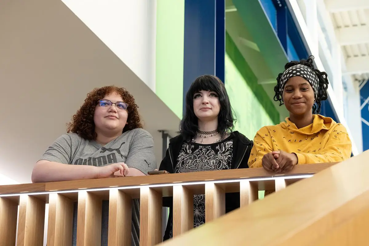 Three OTC students stand together on the upper level of the PMC building during Trivia Night.