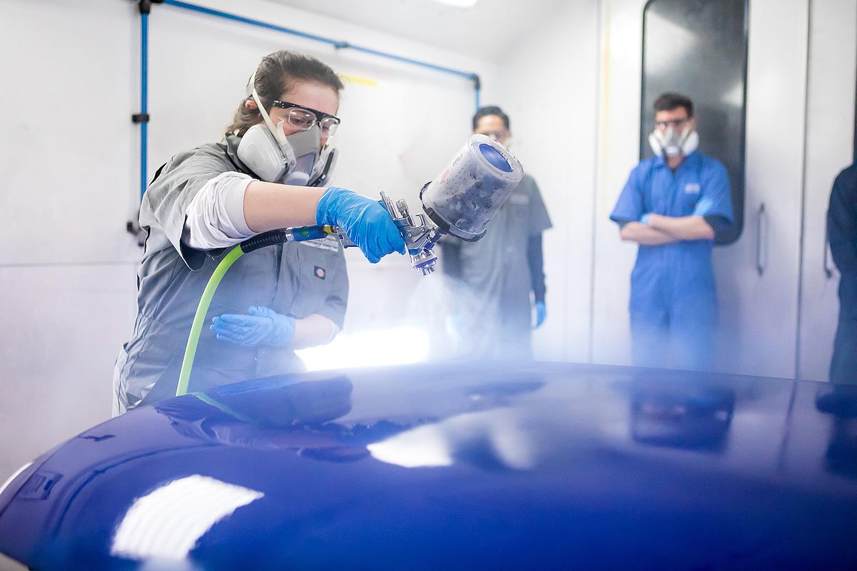 A student in the Auto Collision Repair Program is spraying a car hood.