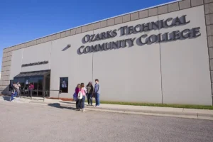 Students stand and talk outside Ozarks Tech’s Lebanon campus building on a sunny day.