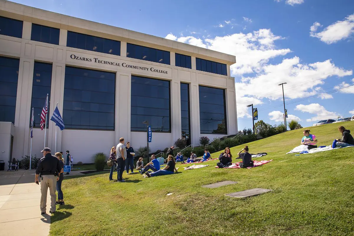 Students sit on the lawn outside Ozarks Technical Community College during a sunny day.