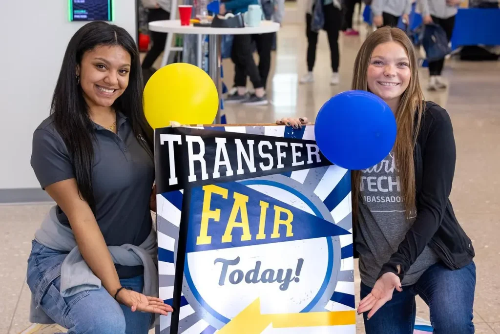 Two women pose with sign board