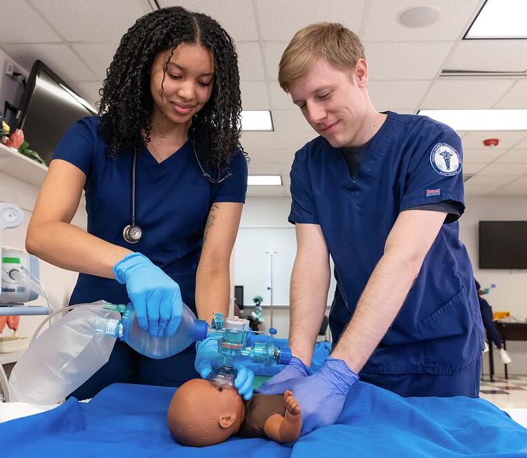 Two students practice respiratory therapy on a mannequin