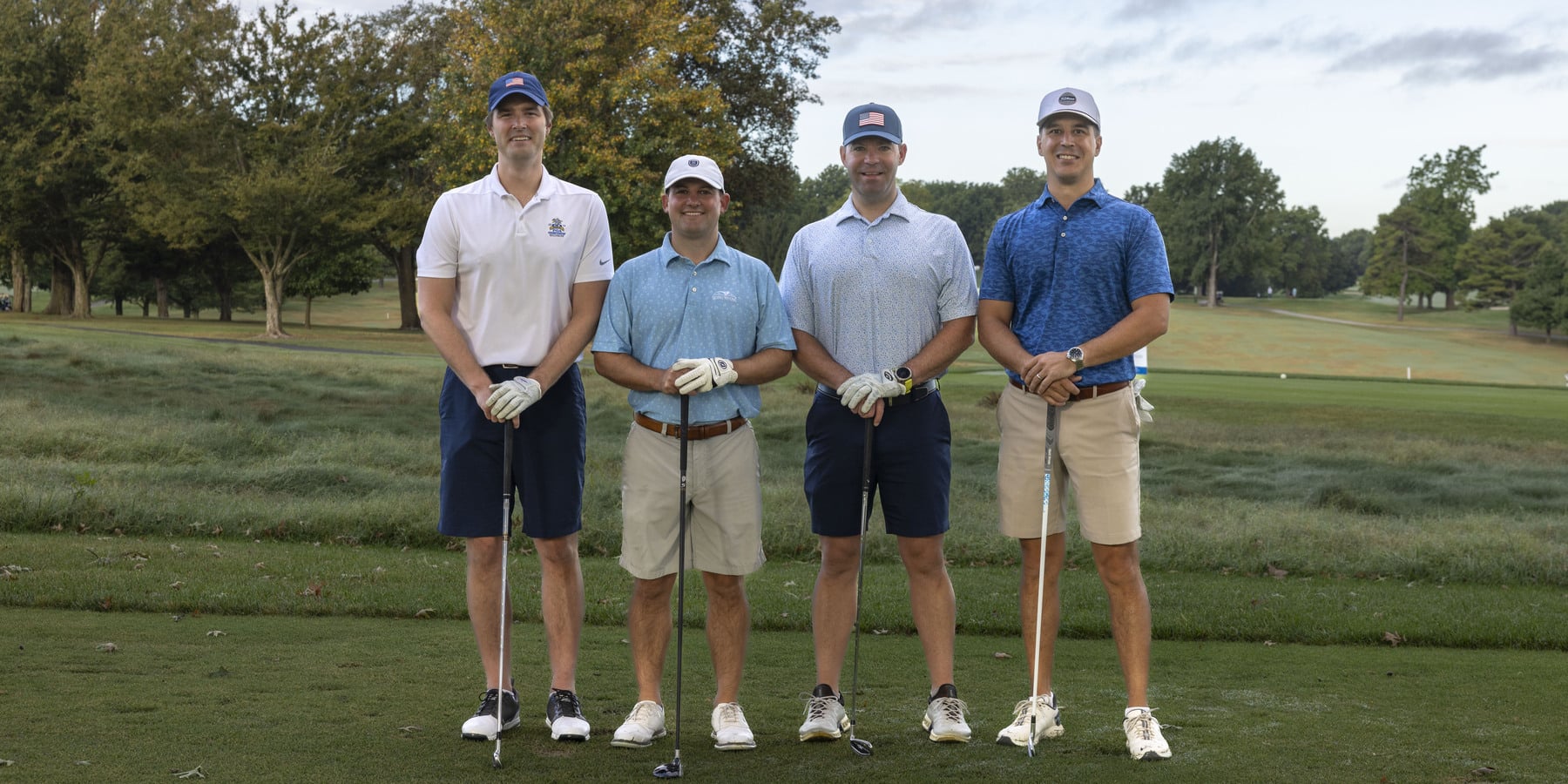 Four golfers are depicted with golf clubs and smiles
