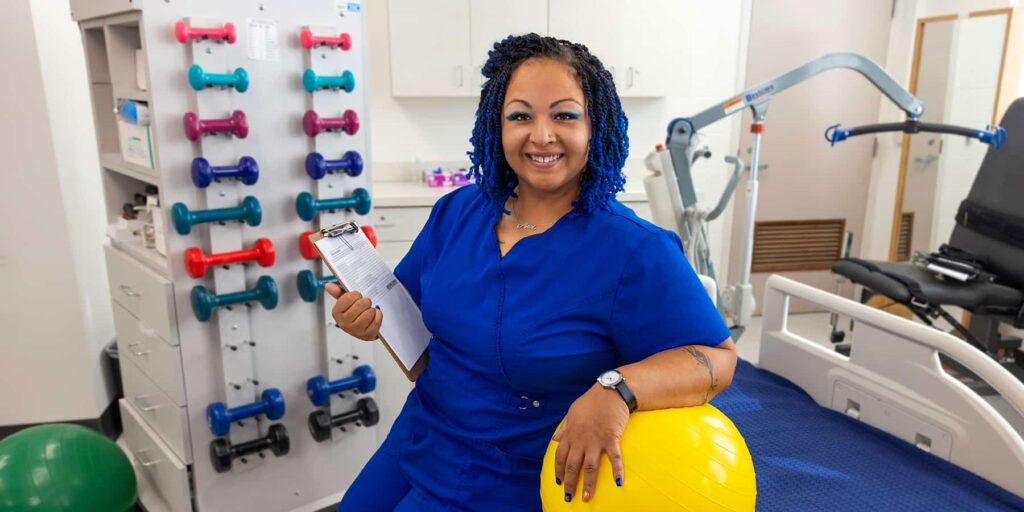 Occupational Therapy Assistant Program student Arica Timmons is depicted holding a small exercise ball and a clipboard