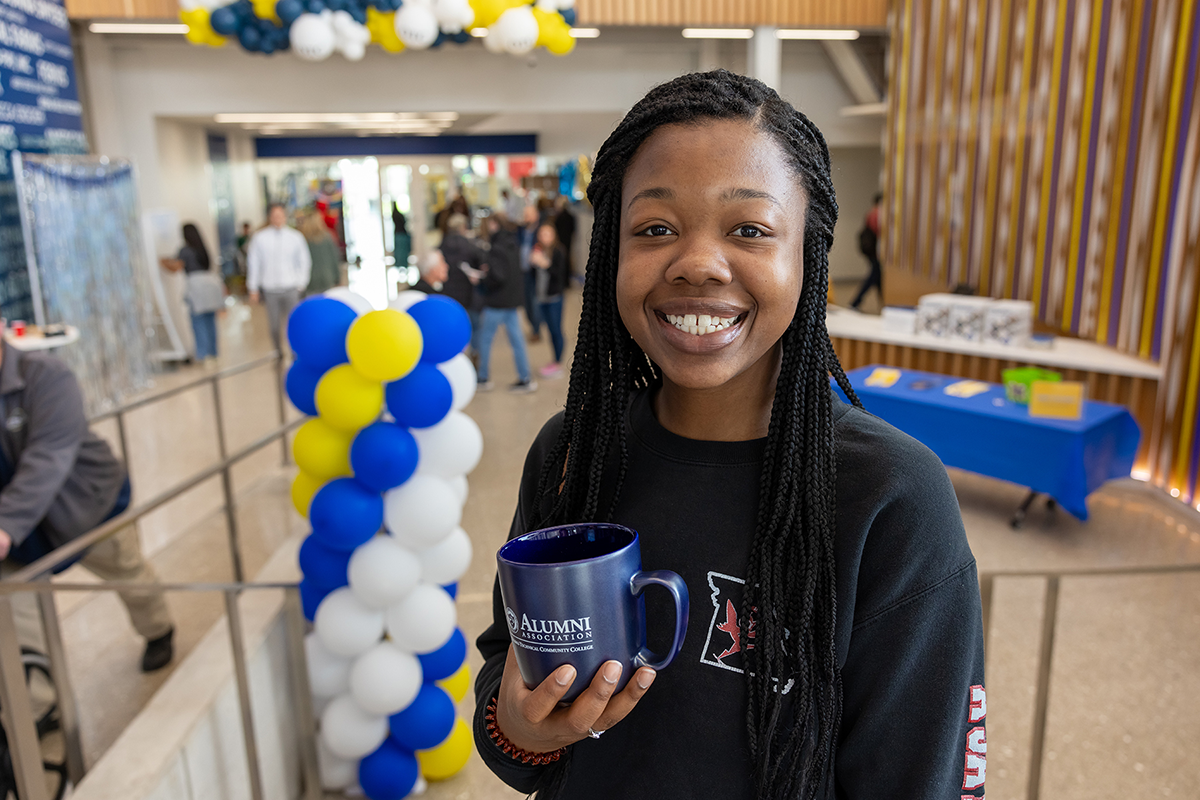 Student holding an Alumni Association coffee mug