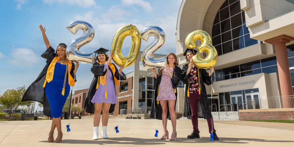 Ozarks Tech graduates are depicted holding balloons spelling out 2023 in front of the Information Commons building.