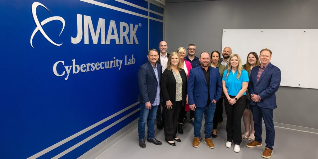 Representatives from JMark and Ozarks Tech are depicted together in a group inside the JMark Cybersecurity Lab