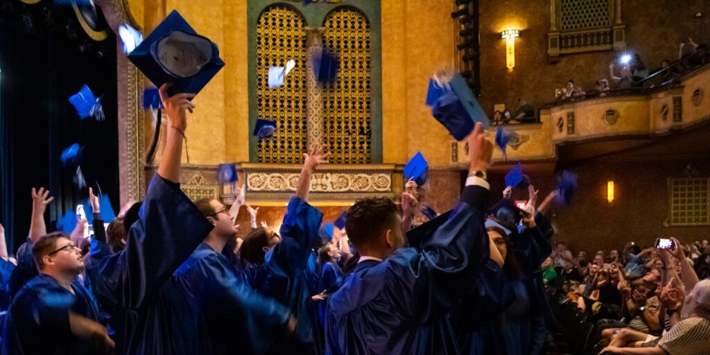 Ozarks Tech Middle College graduates are depicted throwing their caps at a comencement ceremony