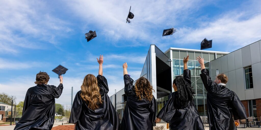 Ozarks Tech graduates are depicted throwing their caps in the air