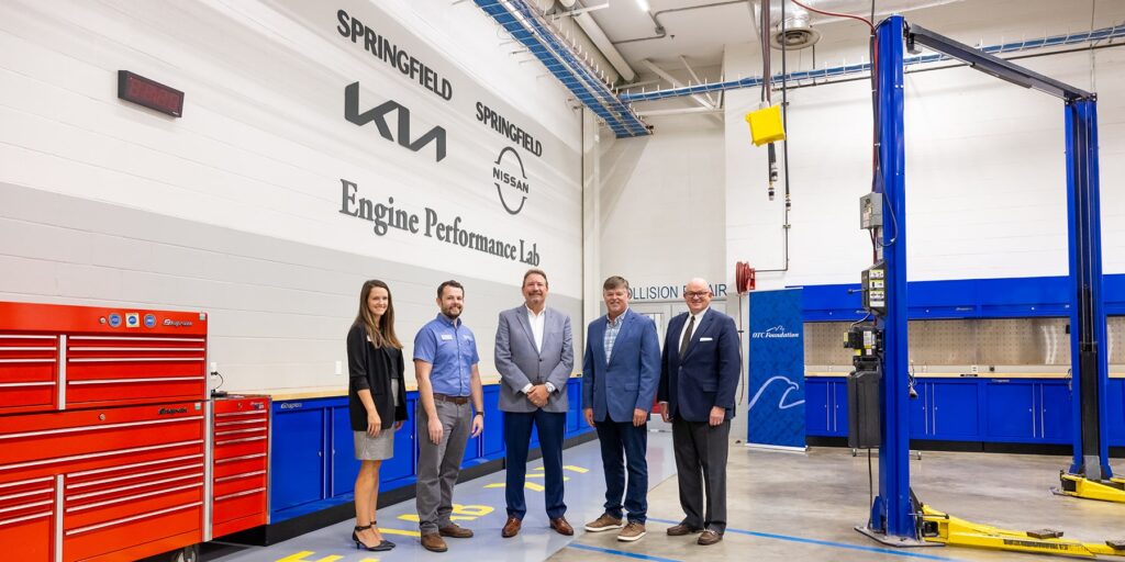 Representatives from Springfield Nissan Kia are depicted observing the Nissan Kia Automotive Engine Lab