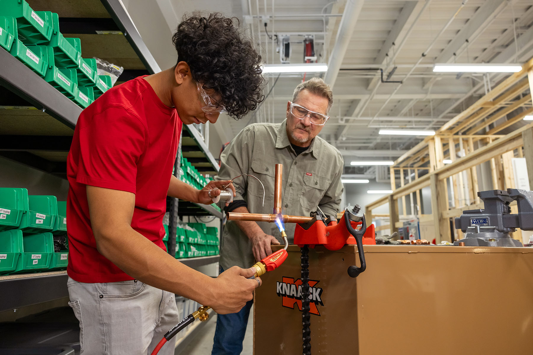 An Ozarks Tech plumbing student is depicted welding copper pipes together