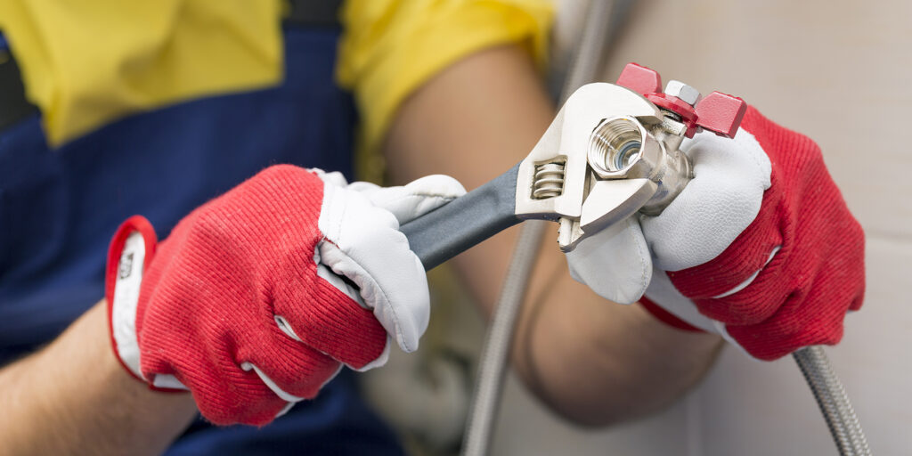An Ozarks Tech plumbing student is depicted unscrewing fittings in a bathroom