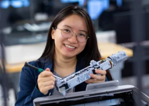 Students holds project in front of 3D printer