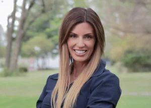 Woman with long hair wearing a blue blazer smiling