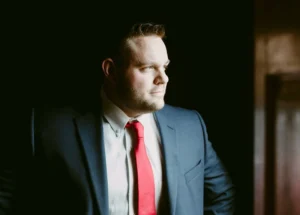 Man wearing a suit and tie stares out of a window