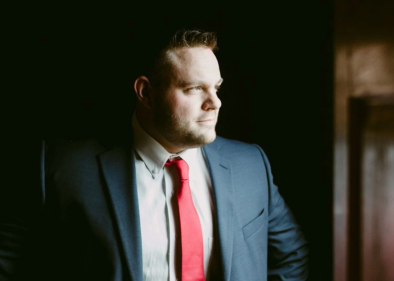 Man wearing a suit and tie stares out of a window