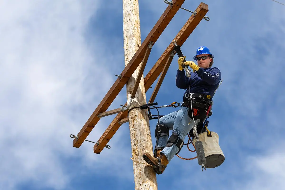 Lineworker climbs pole in safety gear