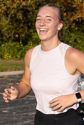A student smiles at the camera while on a run.