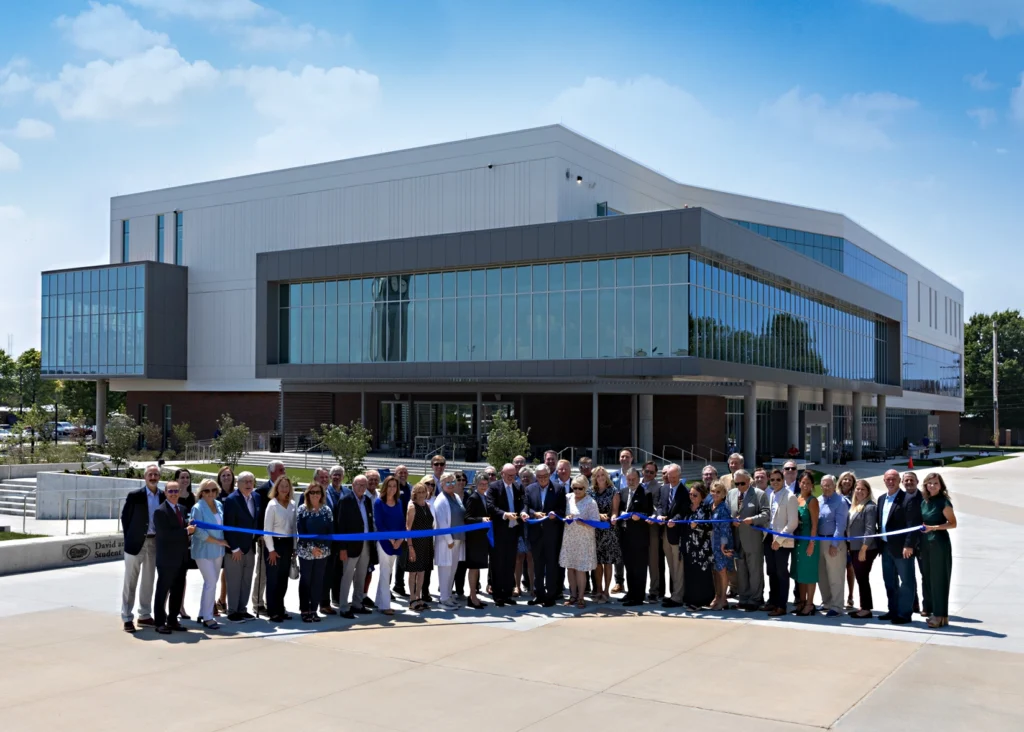 Group of people cut a ribbon in front of The U building at Ozarks Tech campus