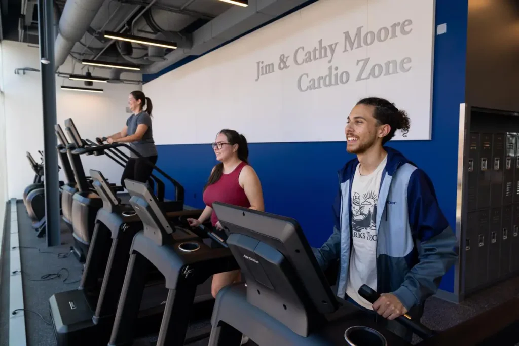 Three students exercise on cardio equipment in the Fitness Center.