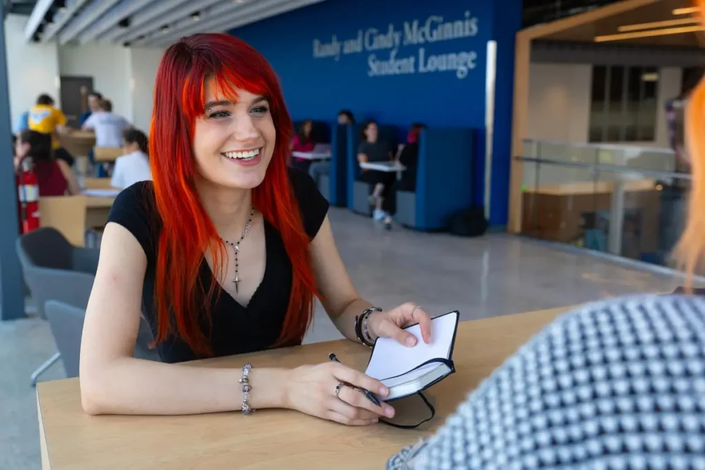 Two students sit at a table in The U and talk.