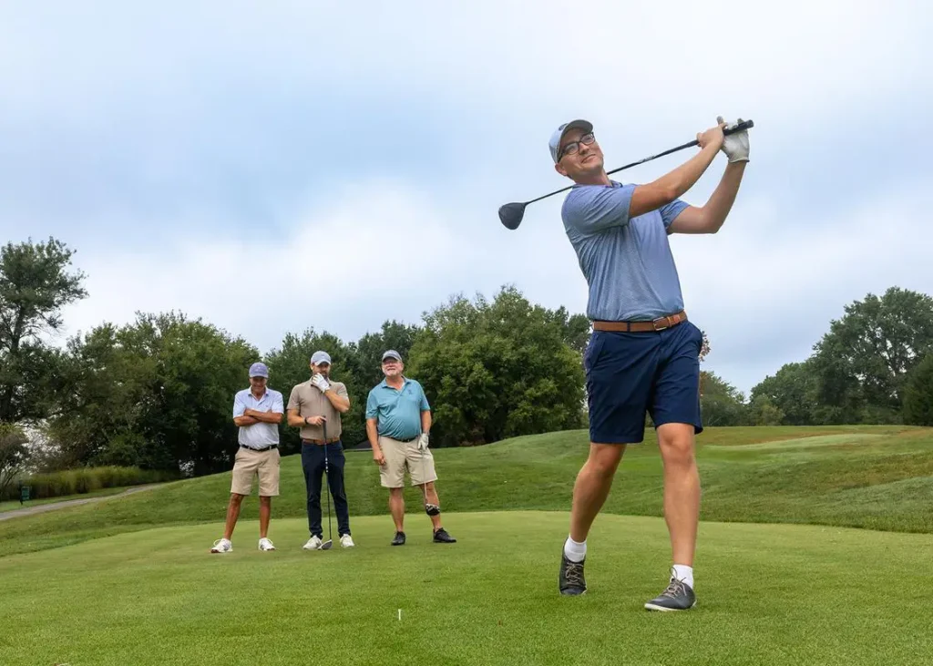 Man swings club at golf tournament